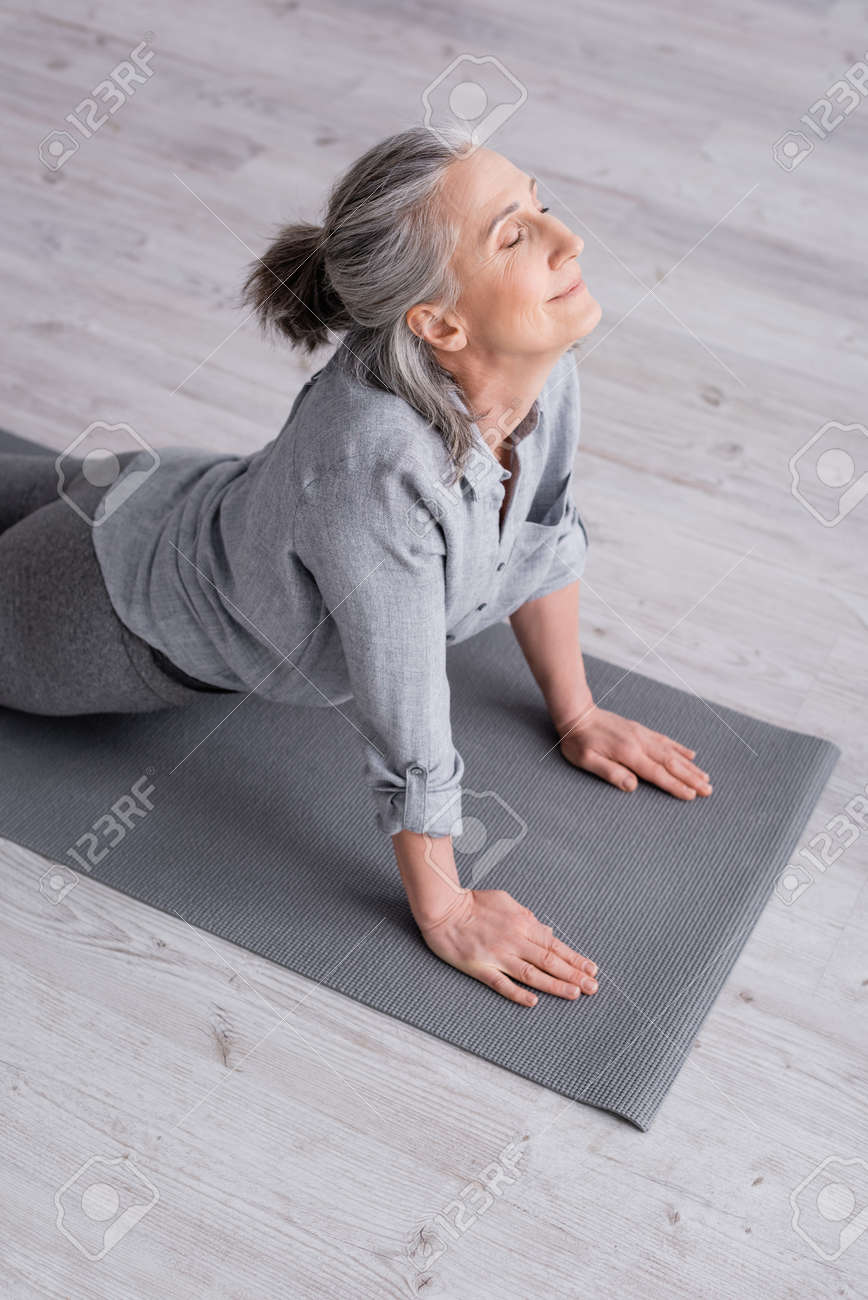 Mujer mediana edad practicando yoga en casa