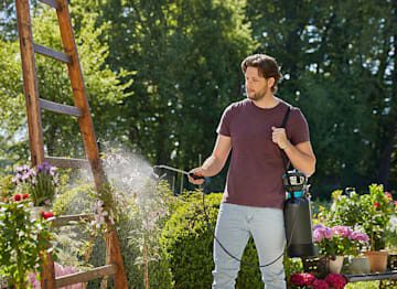 Mujer aplicando insecticida en jardín con mascarilla